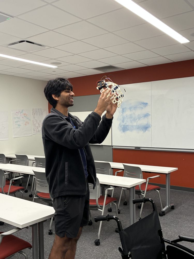 A team member holding up the wired EEG electrode cap to inspect it.